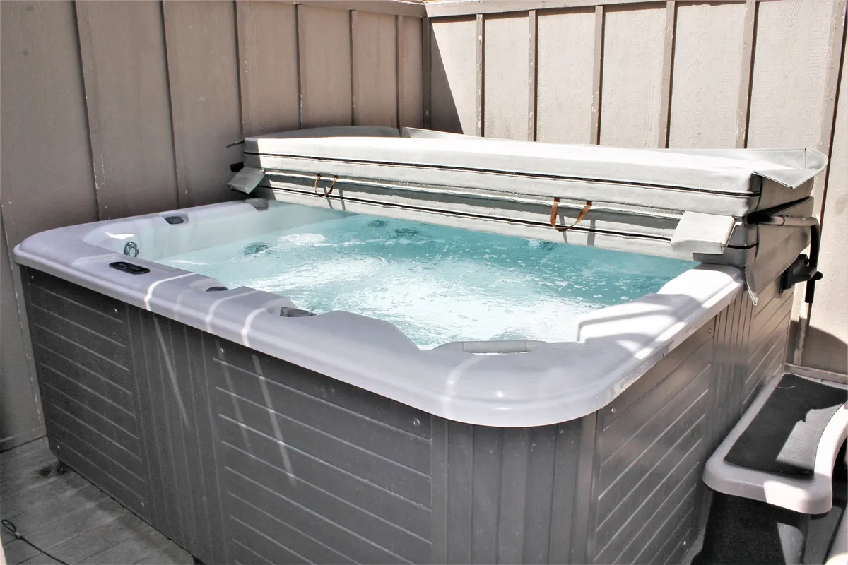 A tranquil outdoor hot tub surrounded by wooden walls, offering a private and relaxing setting for unwinding after an active day. The space feels intimate and perfect for group relaxation.