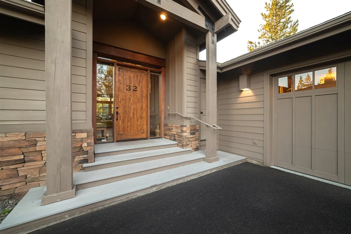 This image showcases the front door of the home with attractive stone accents and spacious steps, creating a welcoming and inviting first impression. The setting suggests immediate access to both the house and the greater amenities surrounding it.