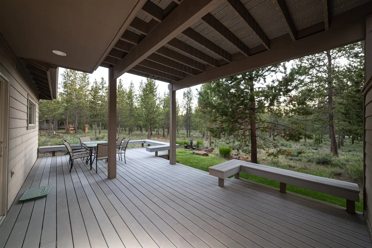 An inviting outdoor seating area nestled in a landscaped garden, surrounded by tall trees. The scene suggests peaceful relaxation, outdoor dining, and the opportunity to enjoy nature, from sunrise coffee to evening stargazing.