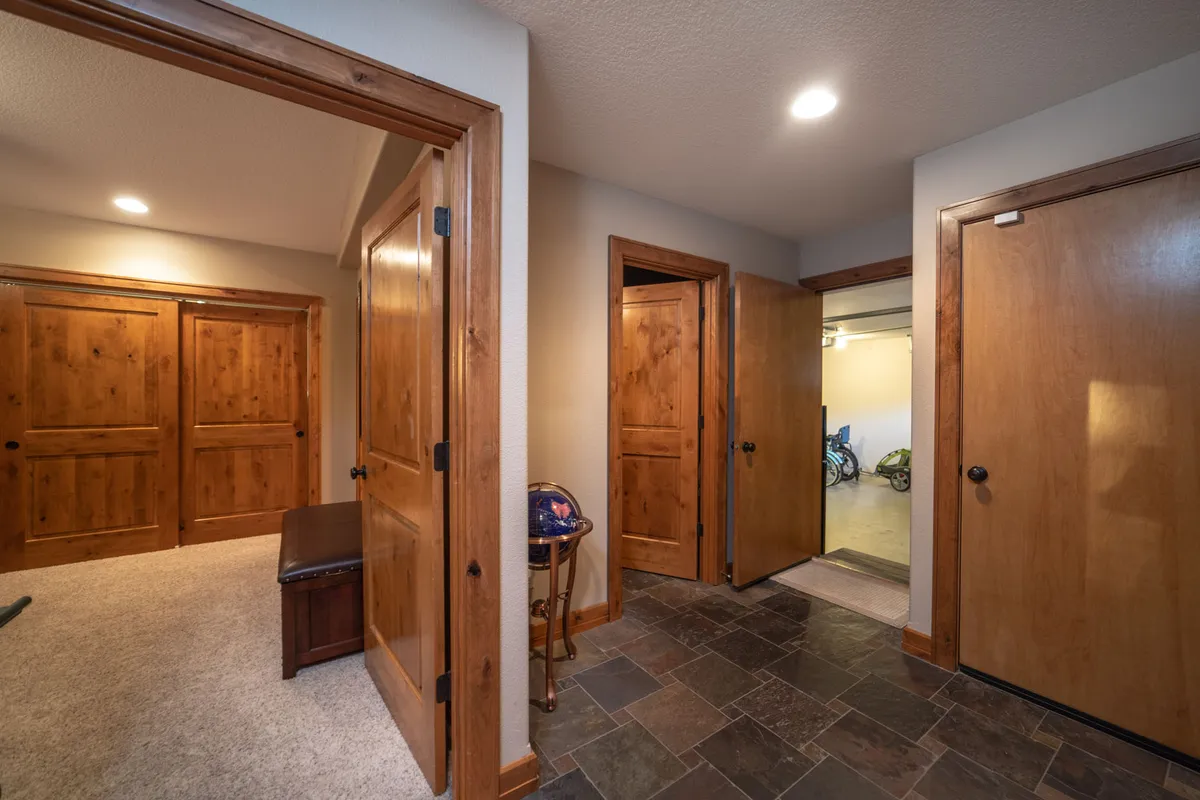 An inviting hallway featuring wooden doors, slate flooring, and a comfortable bench, evoking the experience of entering or exiting the home. The space feels cozy, practical, and ready to welcome guests or family back from local adventures.