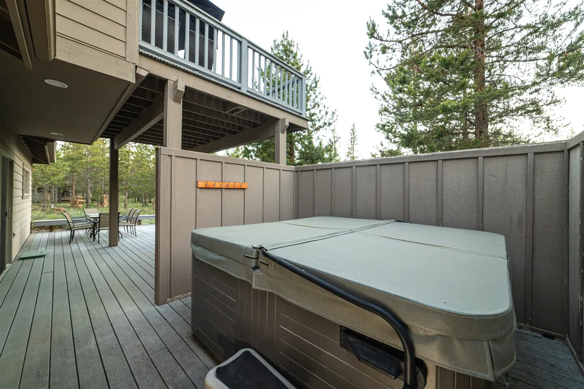 This exterior image features a bubbling hot tub on a spacious deck, surrounded by trees for privacy and tranquility, inviting guests to relax and unwind outdoors.